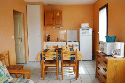 uma cozinha com uma mesa e cadeiras e um frigorífico em EN PLEINE VERDURE AU CALME NON LOIN DU CENTREVILLE em La Tranche-sur-Mer