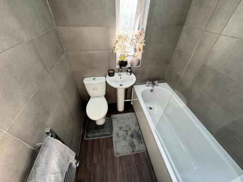 een badkamer met een toilet, een wastafel en een bad bij Home In Coventry in Coventry