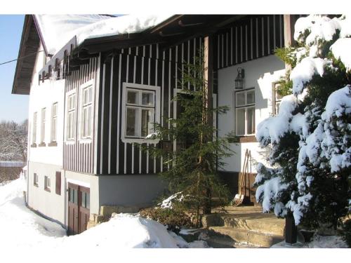 uma casa a preto e branco na neve em Holiday home in a quiet authentic mountain village with a view of the surrounding hills em Zlatá Olešnice