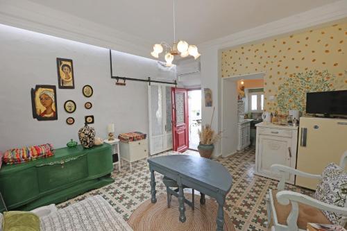 a living room with a green table and a kitchen at Artistic Cycladic House Ano Syros in Ermoupoli