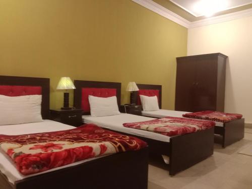 Habitación de hotel con 2 camas con colchas rojas en Regal Guest House, en Bahawalpur