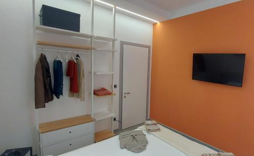 um quarto com armários brancos e uma televisão na parede em unangolodibologna em Bolonha