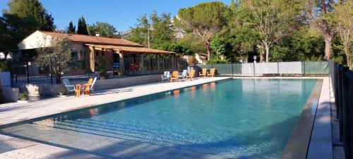 une piscine avec des chaises et une maison dans l'établissement Camping Sainte Victoire, à Beaurecueil