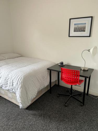 a desk with a red chair next to a bed at ChaRloHub 01 in Coventry