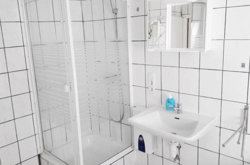 a white bathroom with a sink and a shower at home2stay Worker House Feldstetten Kitchen,Wifi,Smart TV Parking *** in Laichingen