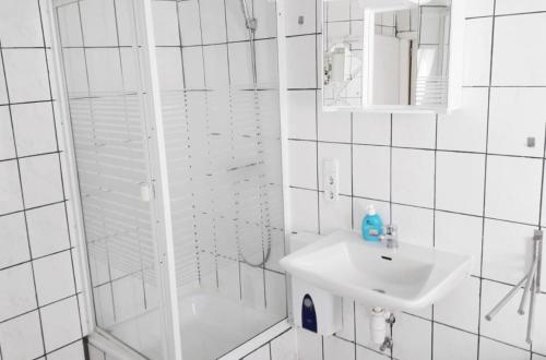 Un baño blanco con lavabo y ducha. en home2stay Worker House Feldstetten Kitchen,Wifi,Smart TV Parking ***, en Laichingen