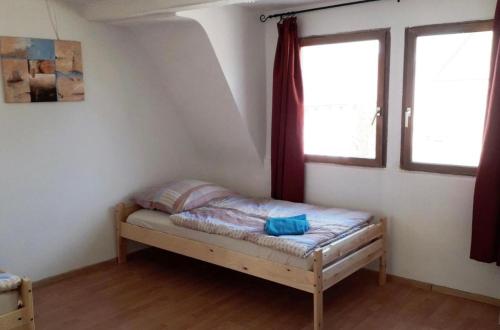 a small bed in a room with two windows at home2stay Worker House Feldstetten Kitchen,Wifi,Smart TV Parking *** in Laichingen