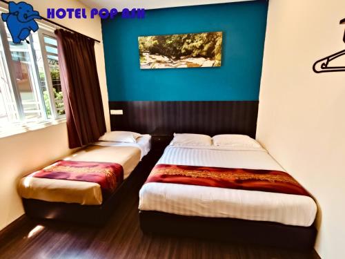 two beds in a room with blue walls at HOTEL POP ASH in Brinchang