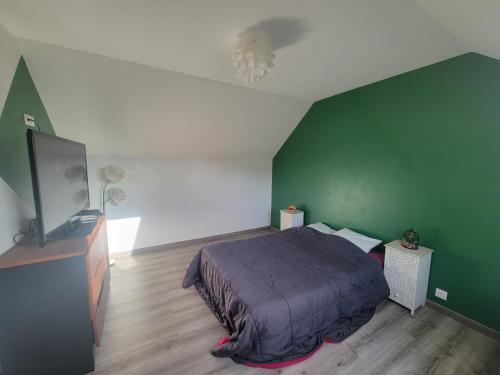 a bedroom with a bed and a green wall at Chambre d'hôtes Goustranville in Goustranville