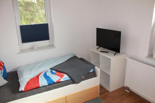 FeWo im Lehm-Fachwerkhaus Erfurt في إرفورت: غرفة نوم صغيرة بها سرير وتلفزيون