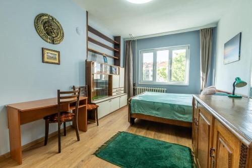 een slaapkamer met een bed, een bureau en een tafel bij 3-BR Central Residence in Sofia