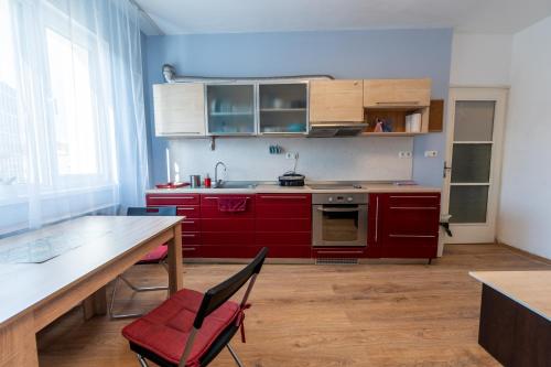 een keuken met rode kasten en een tafel en stoelen bij 3-BR Central Residence in Sofia