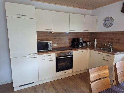 a kitchen with white cabinets and a microwave at Haus Bergblick Bay. Wald in Prackenbach