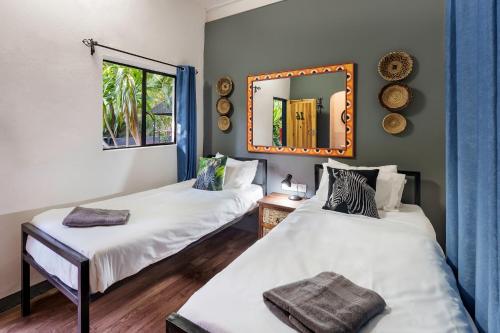 2 camas en una habitación con espejo en la pared en Victoria Falls Backpackers Zambia, en Livingstone