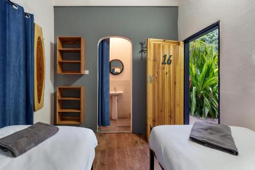 a room with two beds and a door to a bathroom at Victoria Falls Backpackers Zambia in Livingstone