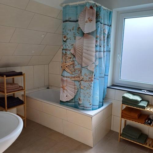 a bathroom with a tub and a shower curtain at Ferienhaus mit 4 Schlafzimmer in Pansdorf