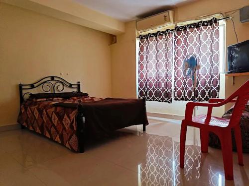 a bedroom with a bed and a chair and a window at Salokhe lodge in Kolhapur