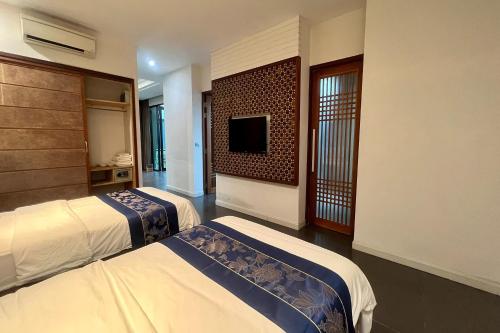 a hotel room with two beds and a flat screen tv at Thai Good Arts Resort in Chiang Mai