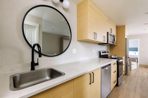 a kitchen with a sink and a mirror at Balcomo - A Ramada By Wyndham in Penticton