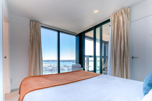 a bedroom with a large bed and large windows at Magnificent SkyTower, Sea, Habour View in CBD in Auckland
