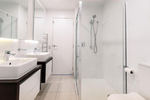 a white bathroom with a shower and a sink at Magnificent SkyTower, Sea, Habour View in CBD in Auckland