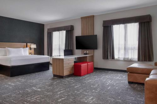 a hotel room with a bed and a desk with a television at Ramada by Wyndham Cochrane in Cochrane