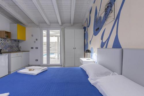 a blue and white bedroom with a bed and a kitchen at La Scala Suite in Realmonte