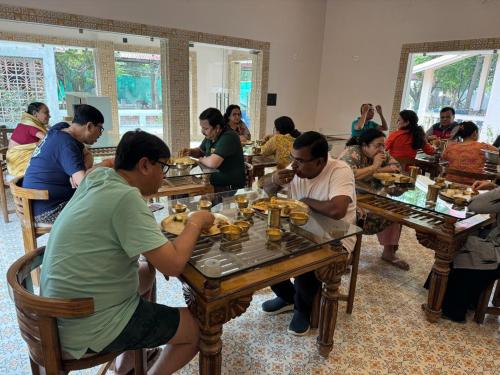 a group of people sitting at tables eating food at SHANTINIKETAN RETREAT, BOLPUR in Shānti Niketan