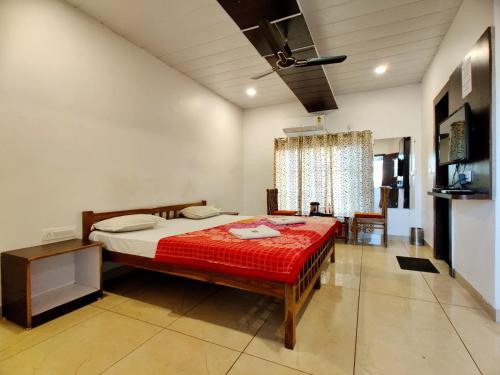 a bedroom with a bed with a red comforter at Chunmun Cottage in Pachmarhī