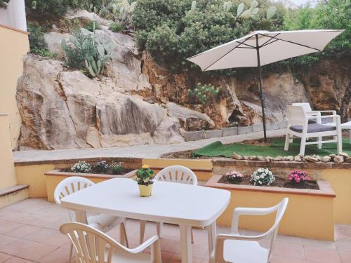 a table and chairs and an umbrella on a patio at Domus DELEDDA 'Sole' in Posada