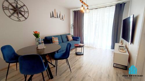 ein Wohnzimmer mit einem blauen Sofa und einem Tisch in der Unterkunft Pod Brzozami Apartamenty Gąski in Gąski