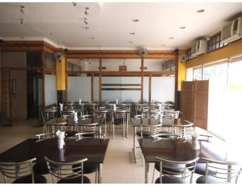 Hotel City Centre, Agartala في آغارتالا: غرفة طعام مليئة بالطاولات والكراسي