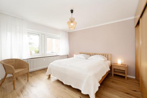biała sypialnia z łóżkiem i krzesłem w obiekcie Stettiner Straße 55 w mieście Grömitz