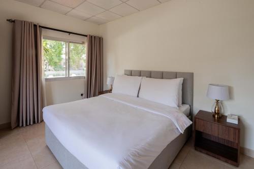 a bedroom with a large white bed and a window at Flamingo Cottages in Manama
