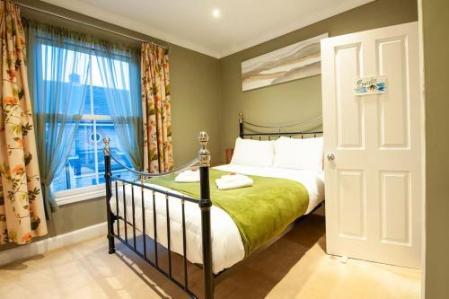a bedroom with a bed with a green blanket and a window at Clifford House - 4 Bed Home Within The City Walls in York