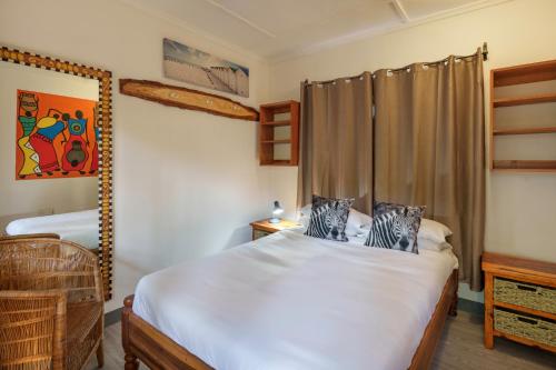 a bedroom with a large white bed in a room at Victoria Falls Backpackers Zambia in Livingstone