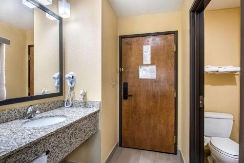La salle de bains est pourvue de toilettes et d'une porte en bois. dans l'établissement Quality Inn & Suites, à Brandenburg