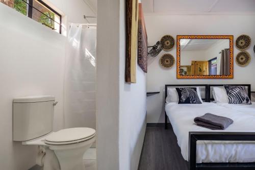een badkamer met een toilet en een bed met een spiegel bij Victoria Falls Backpackers Zambia in Livingstone