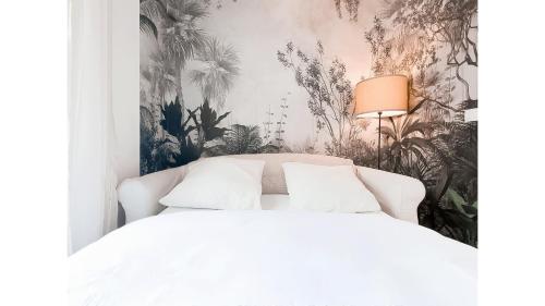 - une chambre avec un lit blanc et un papier peint tropical dans l'établissement Le Vert Neuilly - 10mn Paris, à Clichy