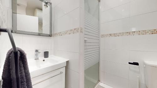 une salle de bain blanche avec un lavabo et un miroir dans l'établissement Le Vert Neuilly - 10mn Paris, à Clichy