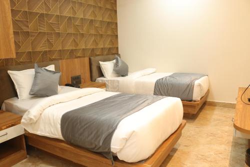 una camera con due letti e una parete di Hotel maxsun gwalior a Gwalior