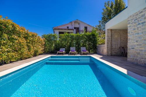 een zwembad met twee paarse stoelen naast een huis bij Apartman SIORA in Njivice
