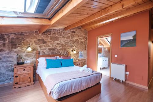 a bedroom with a bed and a stone wall at Entre Pedra e Mar by Serendipia Turismo in Goyanes