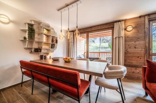 une salle à manger avec une table en bois et des chaises rouges dans l'établissement Apartment Colibri Les Gets - by EMERALD STAY, aux Gets