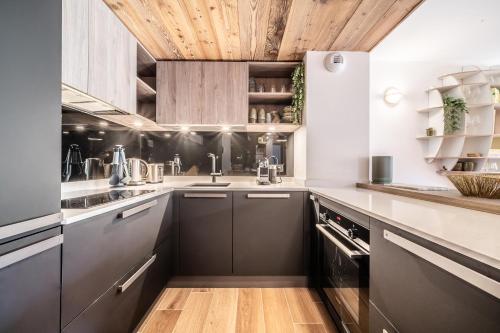 d'une cuisine avec des armoires noires et un plafond en bois. dans l'établissement Apartment Colibri Les Gets - by EMERALD STAY, aux Gets