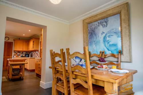 Guest Homes - Longscroft Manor في برادفورد أون آفون: غرفة طعام مع طاولة و لوحة على الحائط