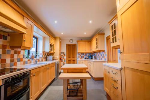 Guest Homes - Longscroft Manor في برادفورد أون آفون: مطبخ كبير مع دواليب خشبية ومغسلة