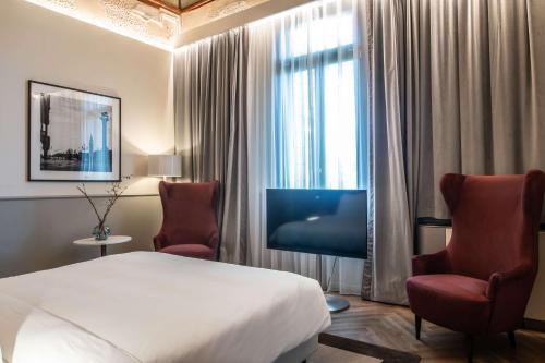 een hotelkamer met een bed en twee stoelen bij Radisson Collection Hotel, Palazzo Nani Venice in Venetië