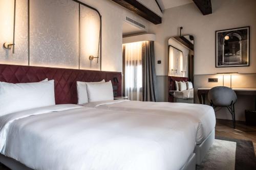 a bedroom with a large white bed and a desk at Radisson Collection Hotel, Palazzo Nani Venice in Venice