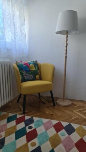 a living room with a yellow chair and a lamp at Apartman Zlatovo Stan Na Dan in Požarevac